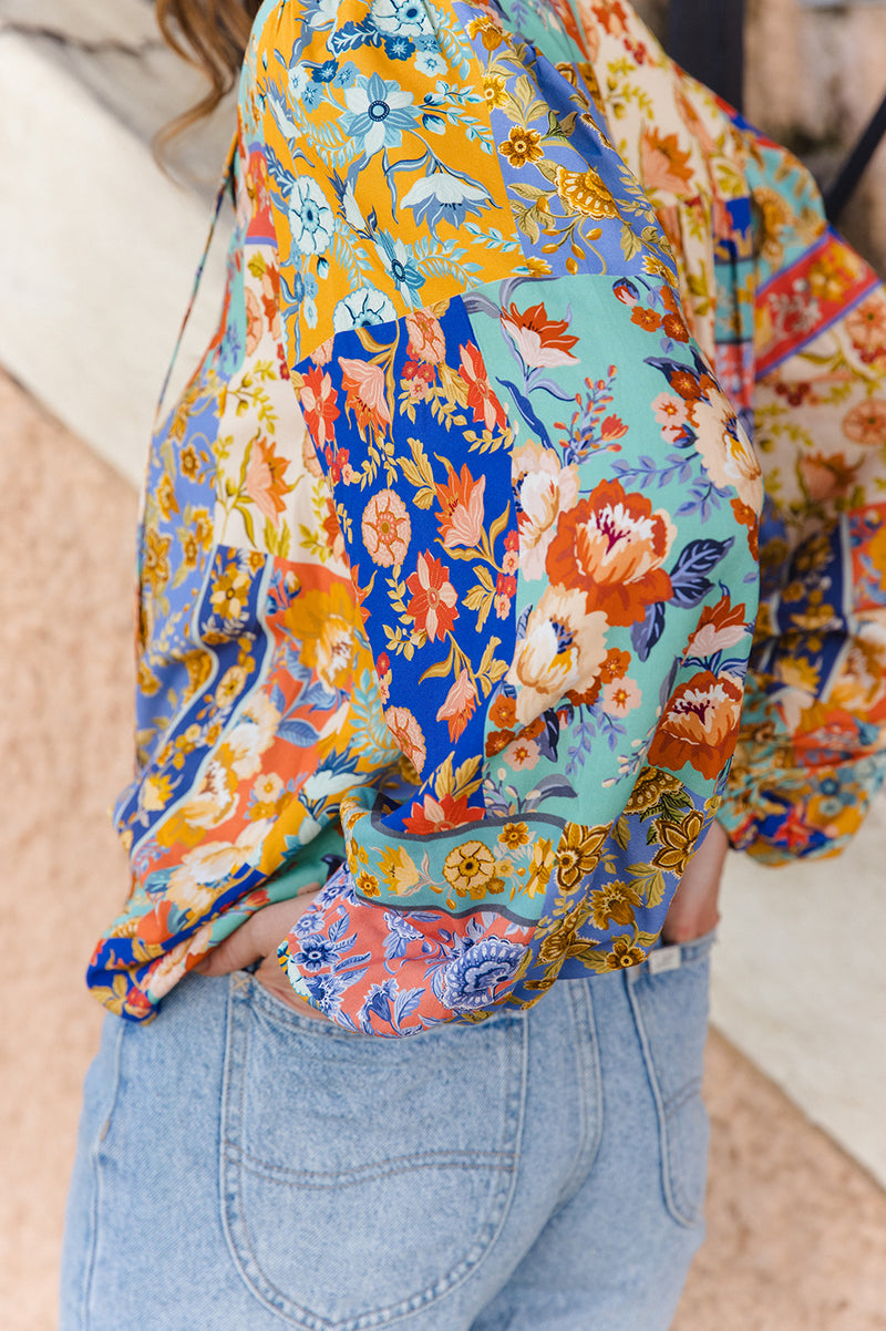 Person wearing a colorful floral blouse with a blurred background