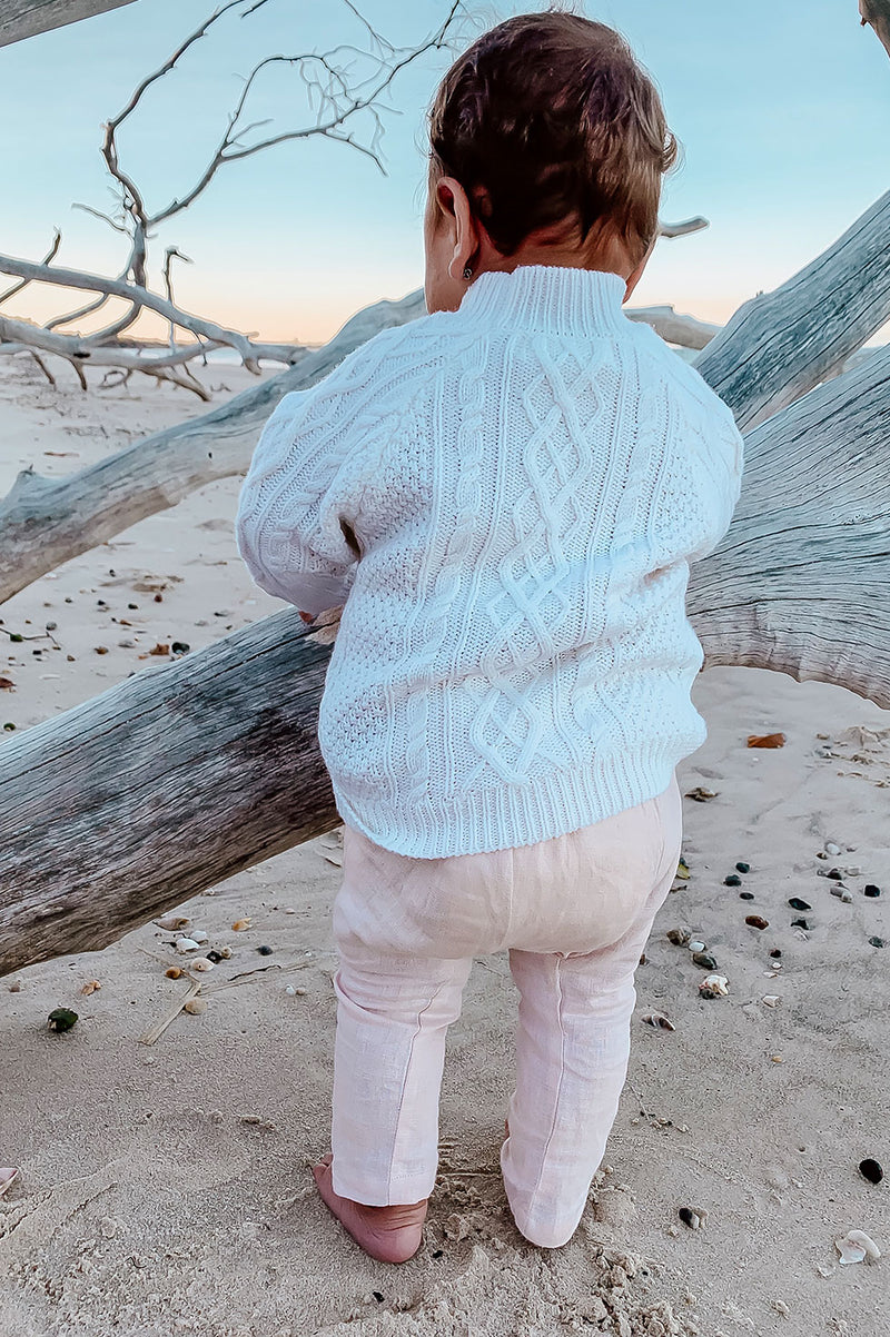 Kids, Bohemian style pant made from pink, 100% linen. Merino Wool cable knit sweater in colour Milk. Exclusive to We the Wild Collective