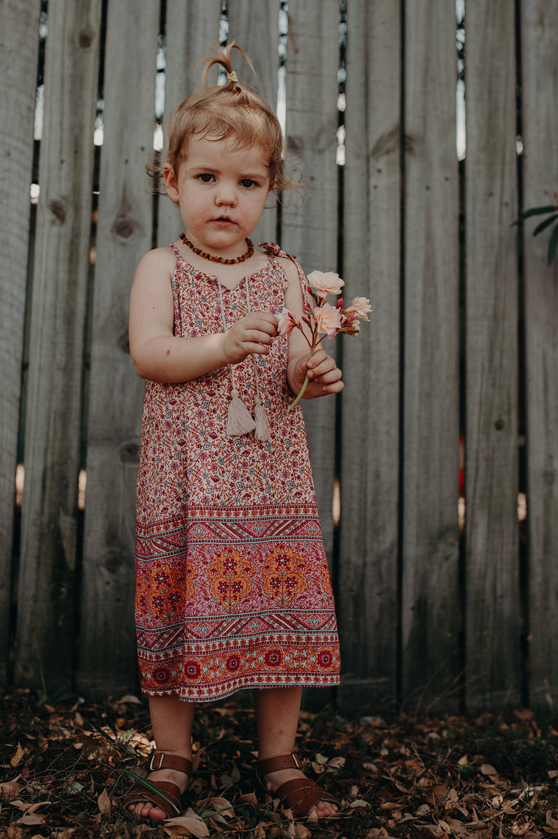 Kids Bohemian inspired, floral printed dress. Adjustable straps, border print and cotton neck tassels. Border floral print in multi colour