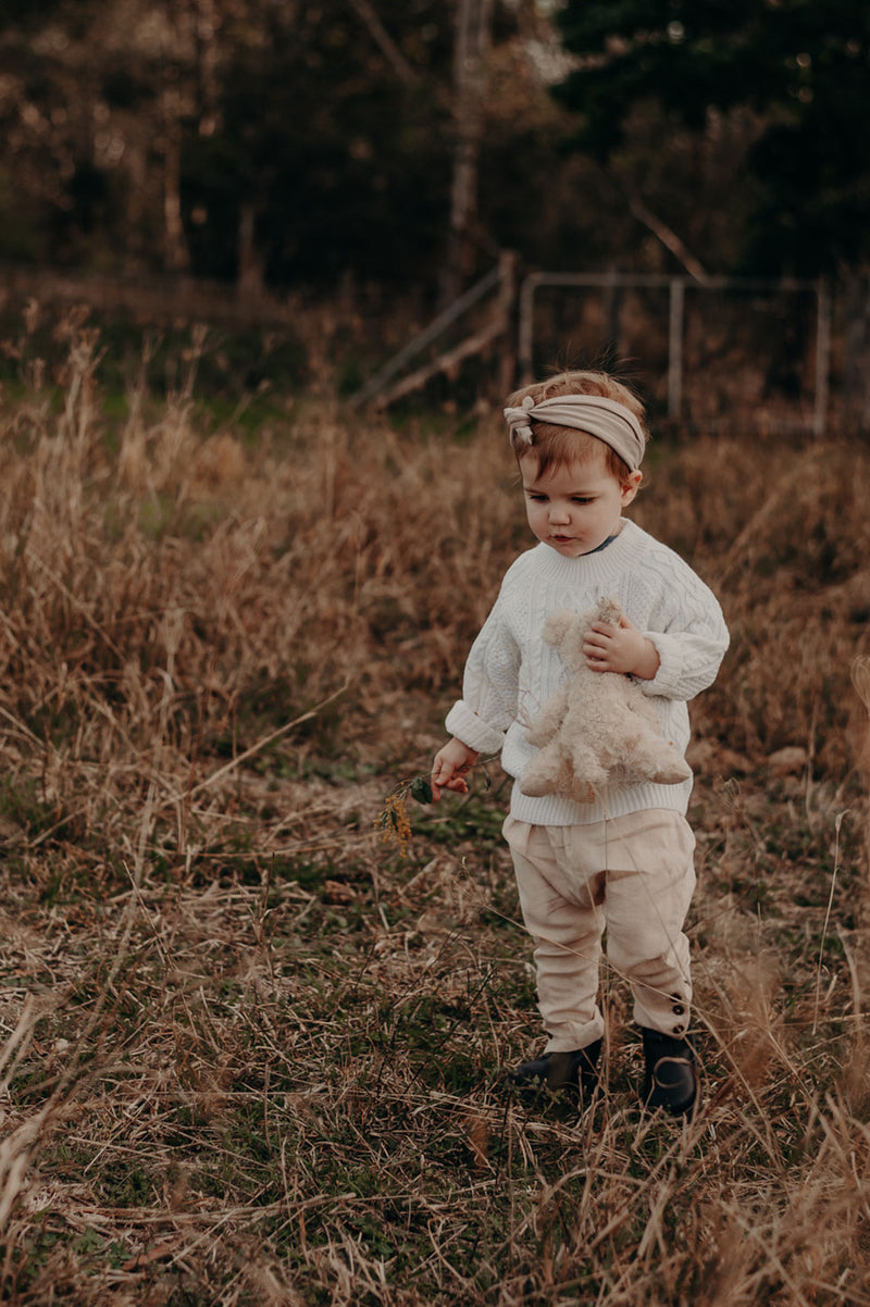 Kids, Bohemian style pant made from pink, 100% linen. Merino Wool cable knit sweater in colour Milk. Exclusive to We the Wild Collective
